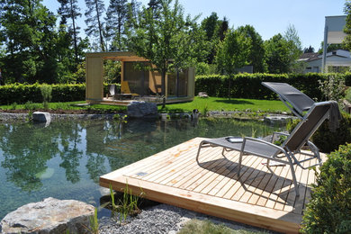 他の地域にある広いコンテンポラリースタイルのおしゃれな裏庭 (池、デッキ材舗装) の写真
