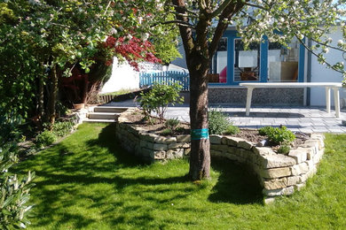 Kleine, Halbschattige Gartenmauer neben dem Haus mit Natursteinplatten in Hannover