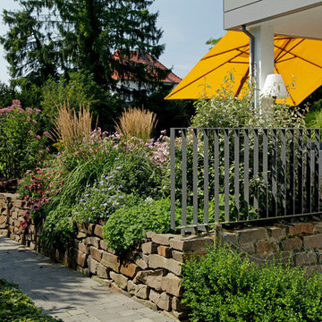 Privatgarten mit Natursteinterrasse und Klinkerwänden