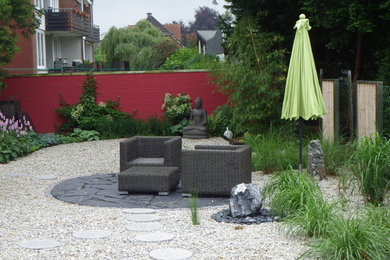 Modelo de jardín asiático de tamaño medio en verano en patio lateral con muro de contención, exposición parcial al sol y adoquines de piedra natural