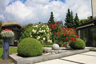 Aménagement d'un grand jardin à la française latéral classique l'été avec un point d'eau, une exposition ensoleillée et des pavés en pierre naturelle.