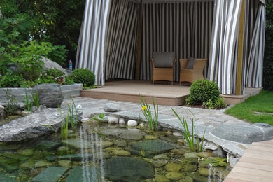 Inspiration for an expansive mediterranean side partial sun garden for summer in Munich with a pond and decking.