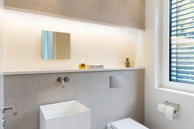 Diseño de aseo contemporáneo pequeño con sanitario de dos piezas, paredes blancas, suelo de madera en tonos medios, lavabo con pedestal y suelo marrón