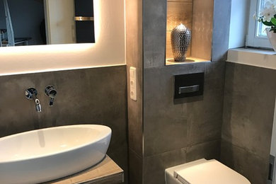Foto di un piccolo bagno di servizio contemporaneo con ante lisce, ante nere, WC a due pezzi, piastrelle nere, pareti bianche, lavabo a bacinella e pavimento grigio