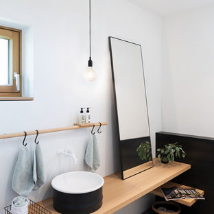 Nordische Gästetoilette mit weißer Wandfarbe, Betonboden, Aufsatzwaschbecken, Waschtisch aus Holz, beiger Waschtischplatte und grauem Boden in München