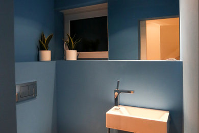 Mittelgroße Moderne Gästetoilette mit Wandtoilette, blauer Wandfarbe, integriertem Waschbecken und braunem Holzboden in Berlin