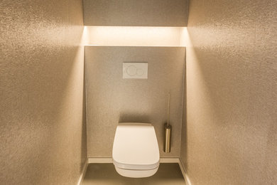 Kleine Moderne Gästetoilette mit Wandtoilette, beigen Fliesen, Mosaikfliesen, beiger Wandfarbe, Betonboden, Sockelwaschbecken, Mineralwerkstoff-Waschtisch und grauem Boden in Sonstige