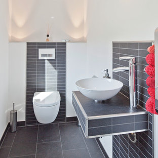 Moderne Gästetoilette mit weißer Wandfarbe, grauem Boden, Toilette mit Aufsatzspülkasten, grauen Fliesen, Aufsatzwaschbecken und grauer Waschtischplatte in Nürnberg