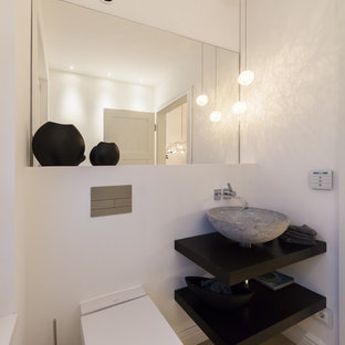 Kleine Moderne Gästetoilette mit offenen Schränken, schwarzen Schränken, Wandtoilette mit Spülkasten, weißer Wandfarbe, hellem Holzboden, Aufsatzwaschbecken, Waschtisch aus Holz, beigem Boden und schwarzer Waschtischplatte in Hamburg