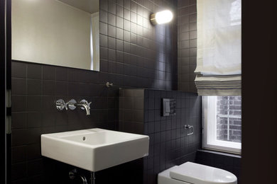 Kleine Moderne Gästetoilette mit Wandwaschbecken, schwarzer Wandfarbe, Wandtoilette und schwarzen Fliesen in Berlin