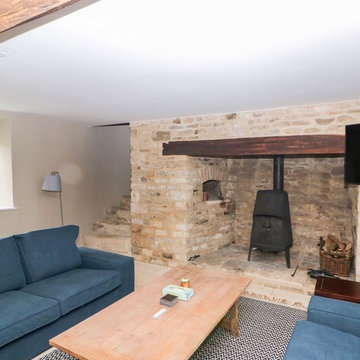 A large, contemporary, C-shaped sofa and log burner in family games and TV room