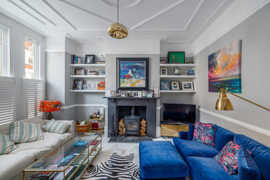 Diseño de sala de estar ecléctica con paredes grises, suelo de madera pintada, estufa de leña, suelo blanco, televisor independiente y alfombra