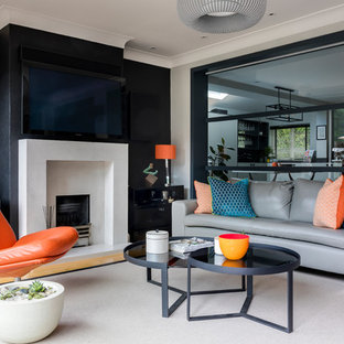 Medium sized contemporary games room in London with a plastered fireplace surround, grey walls, light hardwood flooring, a standard fireplace and a wall mounted tv.