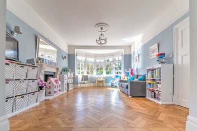 Contemporary games room in Surrey with blue walls and medium hardwood flooring.