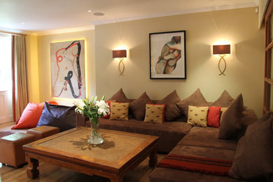 Diseño de sala de estar abierta bohemia grande con paredes amarillas, suelo de madera en tonos medios y televisor colgado en la pared