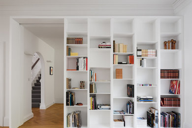 Свежая идея для дизайна: гостиная комната в стиле модернизм с с книжными шкафами и полками, белыми стенами и паркетным полом среднего тона - отличное фото интерьера