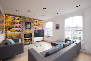 Modelo de sala de estar con biblioteca contemporánea con paredes blancas, suelo de madera clara, chimenea lineal y pared multimedia
