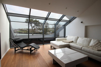 Cette image montre une salle de séjour design de taille moyenne avec un mur blanc et un sol en bois brun.