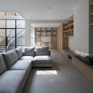 Inspiration for an expansive modern open plan games room in London with white walls, a ribbon fireplace, a plastered fireplace surround, concrete flooring and grey floors.