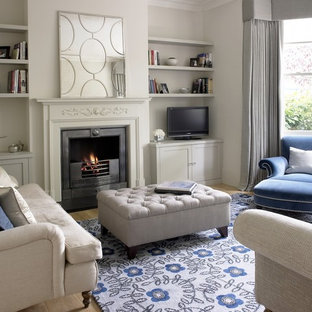 Small elegant enclosed light wood floor and beige floor family room photo in Surrey with gray walls, a standard fireplace, a stone fireplace and a tv stand