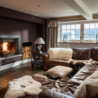 Photo of a large rural enclosed games room in Cornwall with brown walls, a wall mounted tv, grey floors and a standard fireplace.