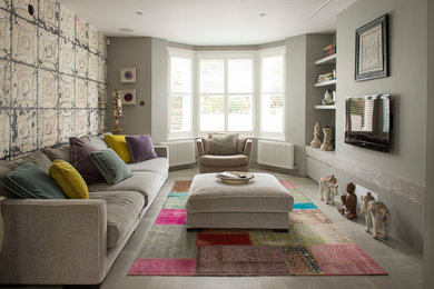 Ejemplo de sala de estar ecléctica con paredes grises, televisor colgado en la pared y suelo gris