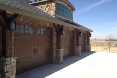 Example of a large mountain style attached three-car garage design in Austin