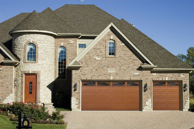 Example of a large transitional attached three-car garage design in Kansas City