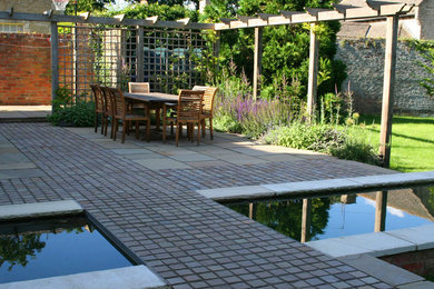 A DINING TERRACE WITH BRIDGE OVER REFLECTIVE 'POOL'