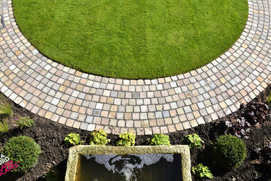 Medium sized courtyard formal garden in Other with a retaining wall and natural stone paving.
