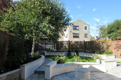 This is an example of a small contemporary back partial sun garden in Other with natural stone paving.