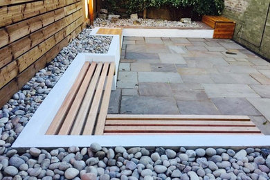 Inspiration for a medium sized contemporary back partial sun garden in Other with a retaining wall and natural stone paving.