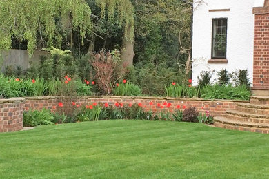 Inspiration for a large classic back full sun garden in London with a retaining wall and natural stone paving.