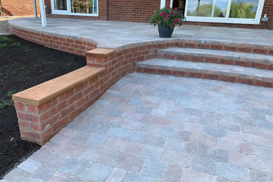 Inspiration for a medium sized contemporary sloped formal full sun garden for summer in Buckinghamshire with a retaining wall and concrete paving.
