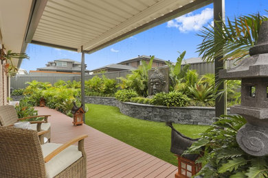 Immagine di un giardino formale tropicale esposto a mezz'ombra di medie dimensioni e dietro casa in estate con un muro di contenimento e pavimentazioni in pietra naturale
