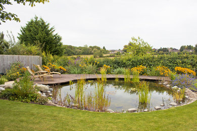 This is an example of a medium sized farmhouse back full sun raised pond for summer in Other with a water feature and decking.