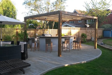 This is an example of a large coastal back full sun garden for summer in Hertfordshire with decking.