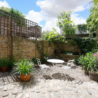 Immagine di un piccolo giardino design esposto a mezz'ombra dietro casa in estate con un muro di contenimento e ghiaia