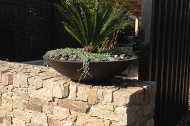 Medium sized contemporary back full sun garden in Melbourne with a retaining wall and natural stone paving.