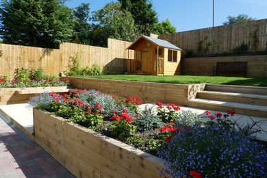 Medium sized contemporary back formal partial sun garden for summer in Glasgow with a retaining wall and brick paving.