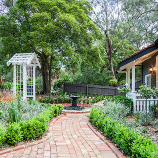 Inspiration for a large traditional front yard full sun garden for spring with brick pavers.