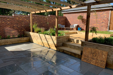 Inspiration for a medium sized mediterranean back formal full sun garden for summer in Buckinghamshire with a raised bed, natural stone paving and a wood fence.