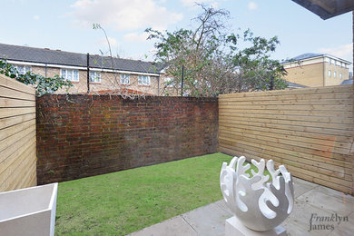 This is an example of a small contemporary back formal partial sun garden for summer in London with concrete paving.