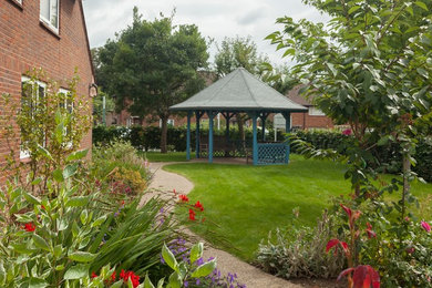 На фото: большой регулярный сад на склоне в классическом стиле с садовой дорожкой или калиткой и полуденной тенью с