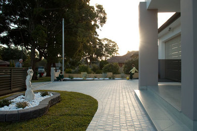 Inspiration for a contemporary front driveway garden in Sydney with natural stone paving.