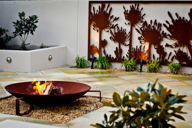 Modelo de jardín minimalista de tamaño medio en verano en patio trasero con brasero, exposición total al sol y adoquines de ladrillo