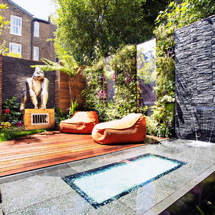 This is an example of a world-inspired back formal garden in London with a water feature and decking.