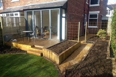 Small contemporary back full sun garden in Manchester with a vegetable patch and decking.