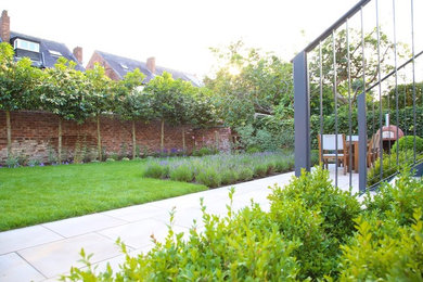 Diseño de jardín moderno pequeño en verano en patio trasero con jardín francés y adoquines de piedra natural