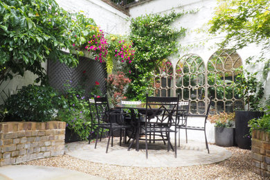 Design ideas for a small victorian courtyard formal partial sun garden for summer in London with a raised bed and natural stone paving.
